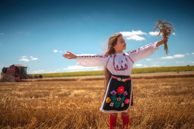 Hasat zamanı tarım buğday tarlasında geleneksel Bulgar folklor kostümlü genç kız sanayi makinesiyle birleştirildi