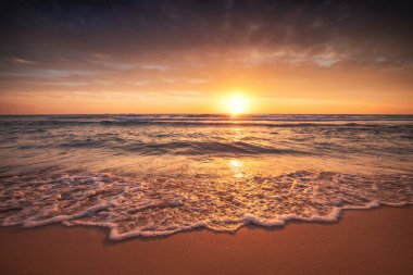 Sahilde çarpıcı plaj günbatımı Canlı renkler ve dindirici dalgalarla