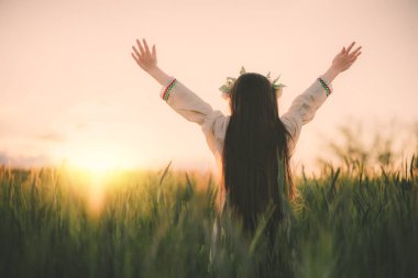 Çiçek şapkalı güzel bir genç kız, geleneksel Bulgar işlemeli etnik folklor elbisesi buğday tarlasında gün batımında