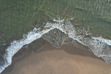 Islak kum, üzerinde küçük okyanus dalgaları var.