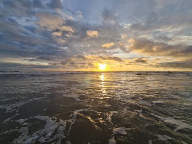 Okyanus dalgaları arka planında açık renkli tropikal gün batımı