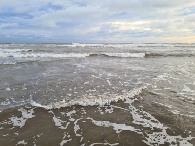 Okyanus sahili, bulutlu havalarda küçük dalgalarla kaplı.