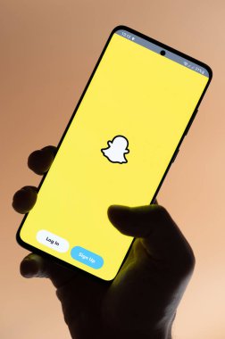 New York, ABD - 4 Kasım 2022: Kahverengi arka planda el altında tutulan akıllı telefon uygulaması