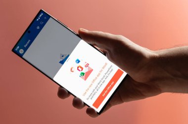 New York, ABD - 10 Kasım 2022: Pembe arka planda Microsoft ofisini akıllı telefon tutarak yakın plan görüntüsü