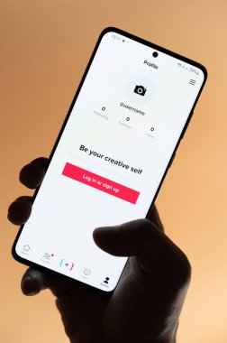 New York, ABD - 4 Kasım 2022: TikTok uygulamasını kullanarak kahverengi arka planda izole edilmiş akıllı telefon uygulaması