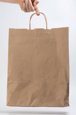 Beyaz stüdyo arka planında bir parmak izole elle tutulan geri dönüştürülmüş kağıt çanta.