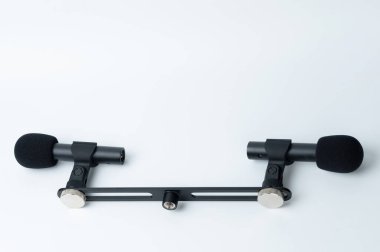 Barda beyaz stüdyo arka planında rüzgar koruması olan iki kardiyot mikrofon var.