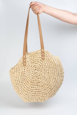 Beyaz stüdyo arka planında izole bir şekilde duran yuvarlak saman plaj çantası.