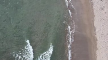 Sığ kıyı şeridi yakınlarında açık yeşil deniz suyu dalgaları