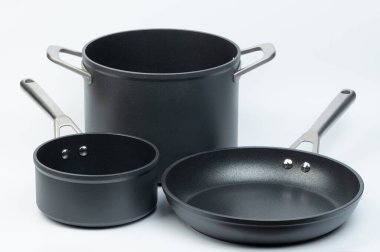 Beyaz stüdyo arka planında geniş ve uzun kulplu boş tencereler.