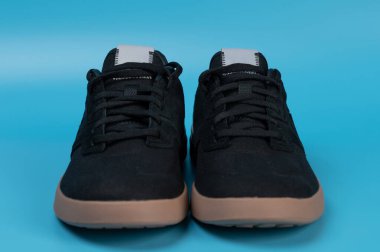 Mavi stüdyo arka planında izole edilmiş siyah günlük ayakkabılar.