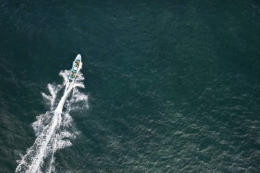Balıkçı teknesi yeşil denizde hızla ilerliyor.