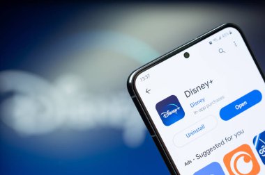New York, ABD - 20 Ağustos 2023: Google mağazasında akıllı telefon ekranındaki Disney + uygulaması bulanık logo arka planına yakın çekim