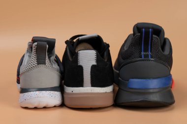 Kahverengi renkli stüdyo arka planında izole edilmiş farklı spor ayakkabılarının arka planı