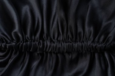 Koyu siyah saten kumaş arka planda dalga dikişleri yakın görünüm