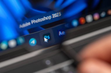 New York, ABD - 11 Temmuz 2023: Adobe Photoshop uygulaması 11 masaüstünde büyüteçle yakından izliyor