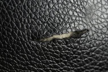 Hasarlı siyah deri kanepe makroyu kapatıyor.