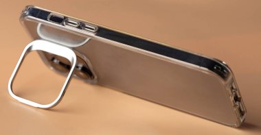 Kahverengi arka planda tripodu olan yatay görünümde akıllı telefon kullanmak