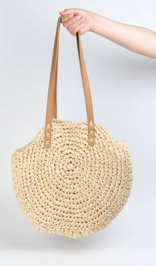 Yaz plajı tarzı kahverengi el çantası beyaz stüdyo arka planında izole edilmiş bir kadına tutun.