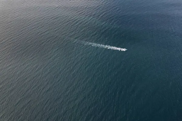 Mavi deniz suyunda hızlı hareket eden küçük balıkçı teknesi. Hava aracı görüntüsü.