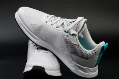 Siyah stüdyo arka planında bağcıkları olan beyaz ayakkabılar.