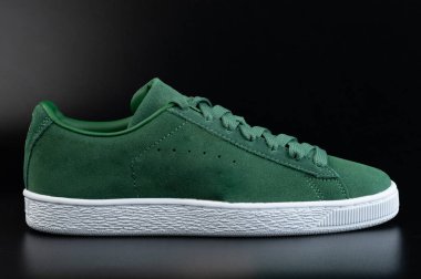 Siyah stüdyo arka planında bağcıklı yeşil bir ayakkabı.