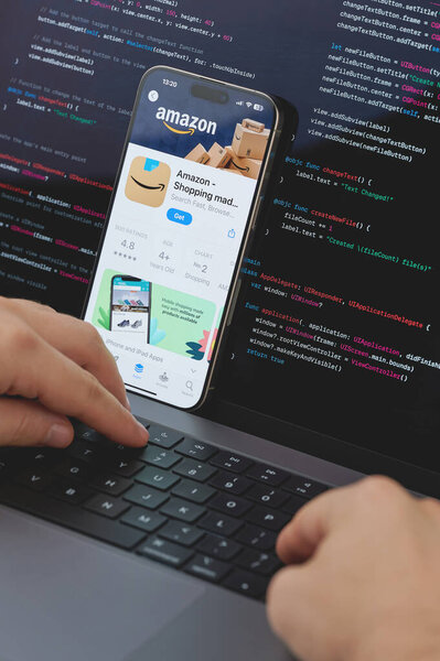 New York, USA - February 23, 2024: Code for new Amazon shopping app in laptop screen with hands on keyboard