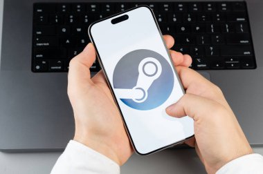 New York, ABD - 6 Nisan 2024: Dizüstü bilgisayarın klavye arka planında akıllı telefon ekranında popüler buhar mobil uygulaması