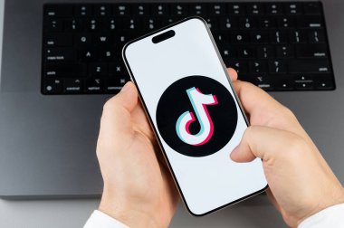 New York, ABD - 6 Nisan 2024: Popüler TikTok mobil uygulaması akıllı telefon ekranında dizüstü bilgisayarın klavye arka planında