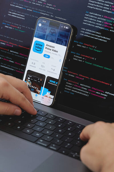 New York, USA - February 23, 2024: Code for new Amazon prime video app in laptop screen with hands on keyboard