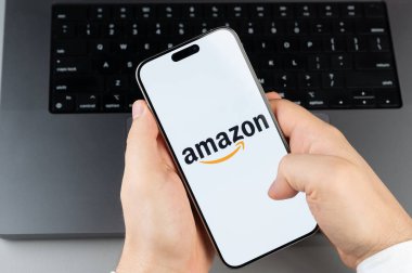 New York, ABD - 6 Nisan 2024: Akıllı telefon ekranındaki popüler Amazon mobil uygulaması dizüstü bilgisayarın klavye arka planında