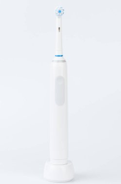 Kablosuz şarj cihazındaki elektrikli diş fırçası beyaz stüdyo arka planında izole edilmiş.