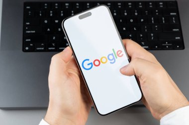New York, ABD - 6 Nisan 2024: Popüler Google mobil uygulaması bilgisayarın klavye arka planında akıllı telefon ekranında