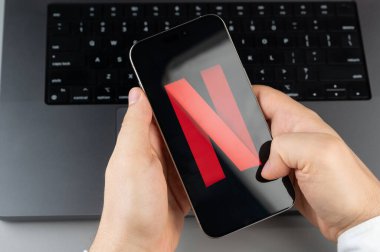 New York, ABD - 6 Nisan 2024: Popüler Netflix mobil uygulaması akıllı telefon ekranında dizüstü bilgisayarın klavye arka planında