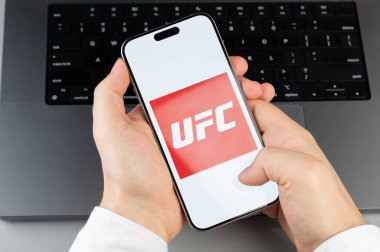 New York, ABD - 6 Nisan 2024: Akıllı telefon ekranındaki popüler UFC mobil uygulaması dizüstü bilgisayarın klavye arka planında