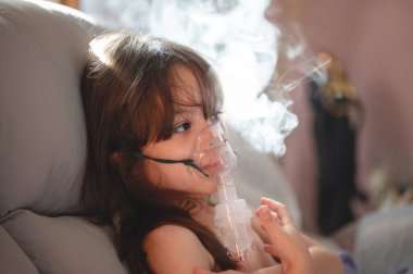 Nebulizör maskeli ve buharlı küçük bir kızın portresi
