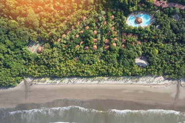 Havuzu, tenis kortu ve deniz kıyısı kıyı şeridi insansız hava aracı manzaralı tropikal doğada lüks bir otel.