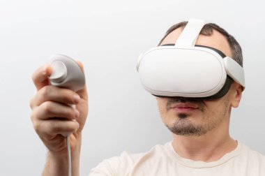 İnsan sanal gerçeklik kulaklığı takar, kontrolörü elinde tutarken dalgın deneyime konsantre olur..