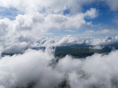 Parlak mavi gökyüzünün altındaki yemyeşil tarlaların üzerindeki tüylü bulutların nefes kesici manzarası doğanın güzelliğini gözler önüne seriyor..
