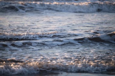 Sakin okyanus dalgaları, güneş ışığının alacakaranlıkta sudan yansıması gibi rahatlatıcı bir ritim yaratır..