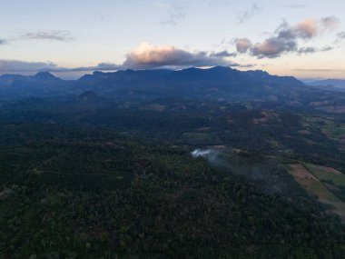 Gün batımında yemyeşil yemyeşil ortamda yükselen dumanla yuvarlanan tepelerin ve dağların nefes kesici manzarası..
