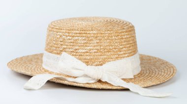 Stüdyo arka planında beyaz fiyonklu kahverengi hasır şapka.