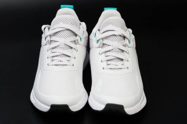 Siyah stüdyo arka planında izole edilmiş bağcıklı beyaz ayakkabılar.