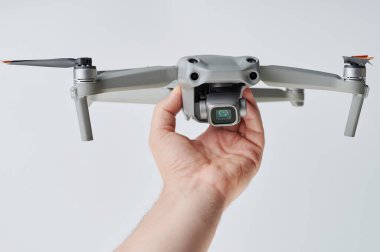 Beyaz stüdyo arka planında el ele tutuşan küçük drone