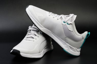 Siyah stüdyo arka planına yakın bağcıklı beyaz ayakkabılar.