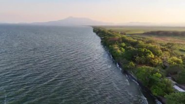 Gölün nefes kesen günbatımı manzarası kıyı boyunca ve uzak dağlar boyunca yemyeşil ağaçlar, huzuru artırıyor..