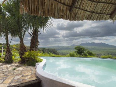 Sonsuz havuz bulutlu bir günde uzak dağlar ve yemyeşil manzaralar sunar..