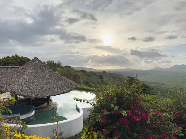 Misafirler huzurlu bir şekilde inzivaya çekilip canlı çiçekler ve günbatımı gökyüzü ile dolu tepelere bakıyorlar..