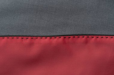 Pürüzsüz gri kumaş bölümünün tekstil görüntüsü koyu kırmızı kesim dikişlerle birleştirilmiştir..