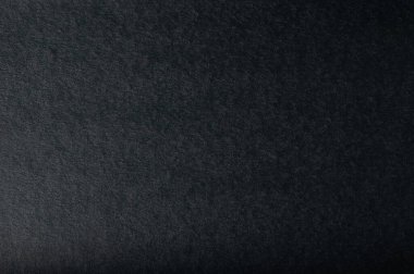 Pürüzsüz siyah kağıt yüzeyine yakın çekim, yaratıcılık projeleri veya sunumlar için mükemmel doku ve derinlik.